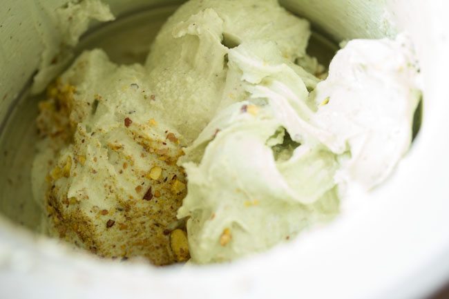 folding pista ice cream with chopped pistachios