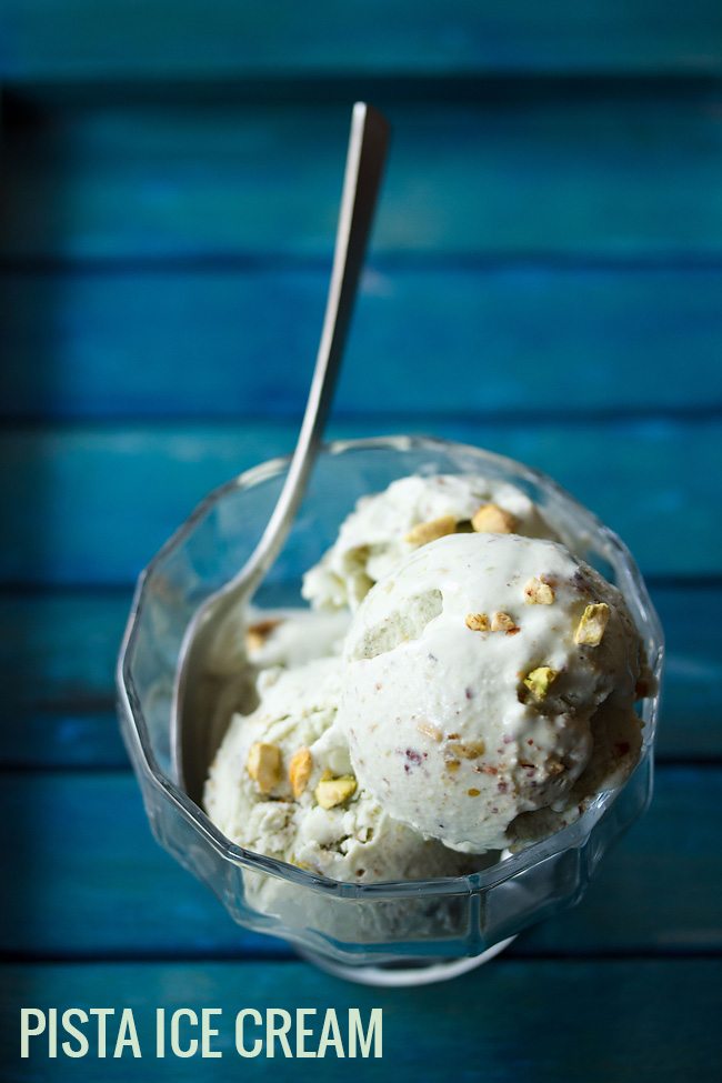 pistachio ice cream scoops in bowl with a spoon on blue table