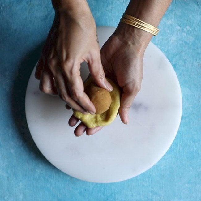 placing stuffing ball in the flattened dough ball for making bobbatlu recipe. 