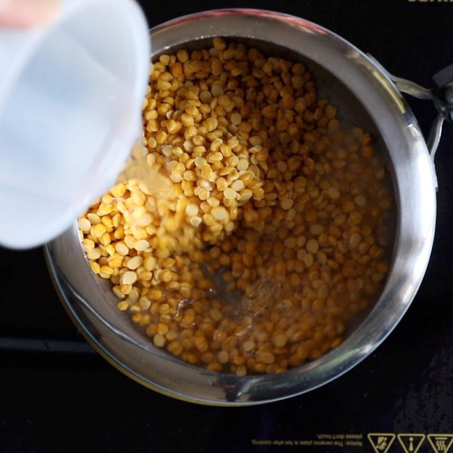 chana dal and water added to pressure cooker for making sweet stuffing for holige recipe. 
