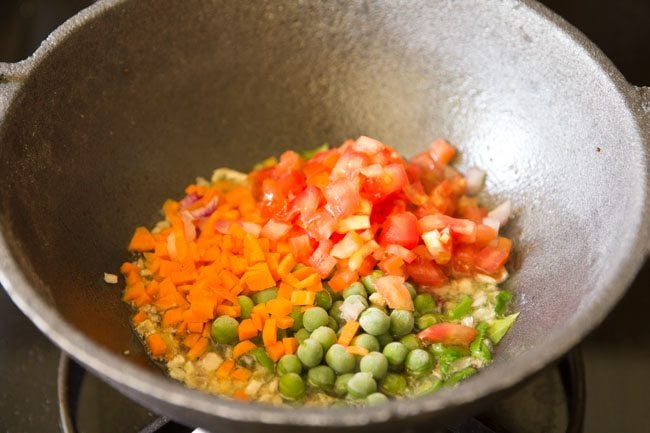 finely chopped carrots and tomatoes, and green peas added to pan. 