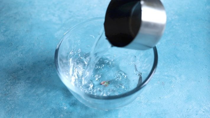 pouring warm water in a bowl for thandai recipe. 