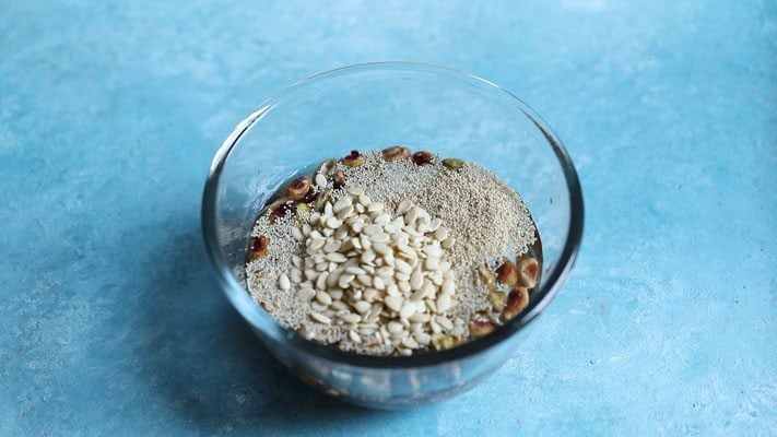 melon seeds floating on water in a glass bowl placed on a bright light blue board