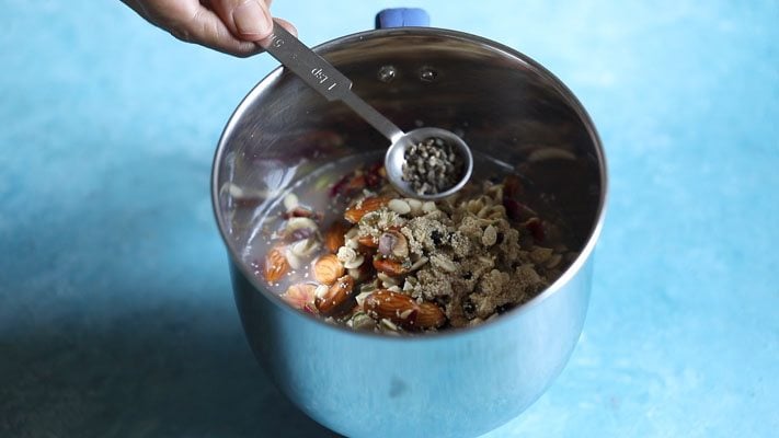 adding green cardamom seeds in the grinder jar for making thandai paste. 