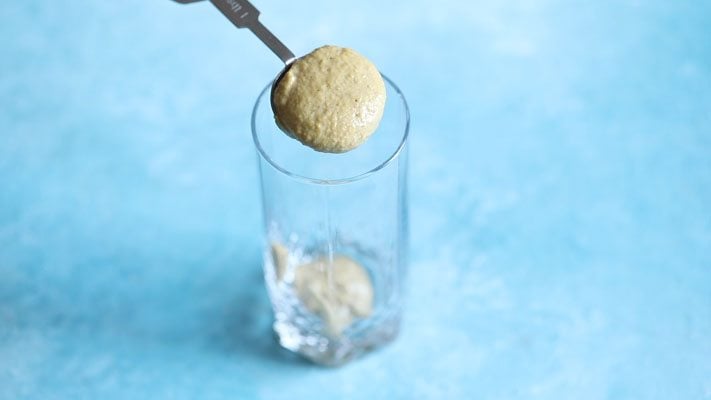 adding thandai paste in a glass. 