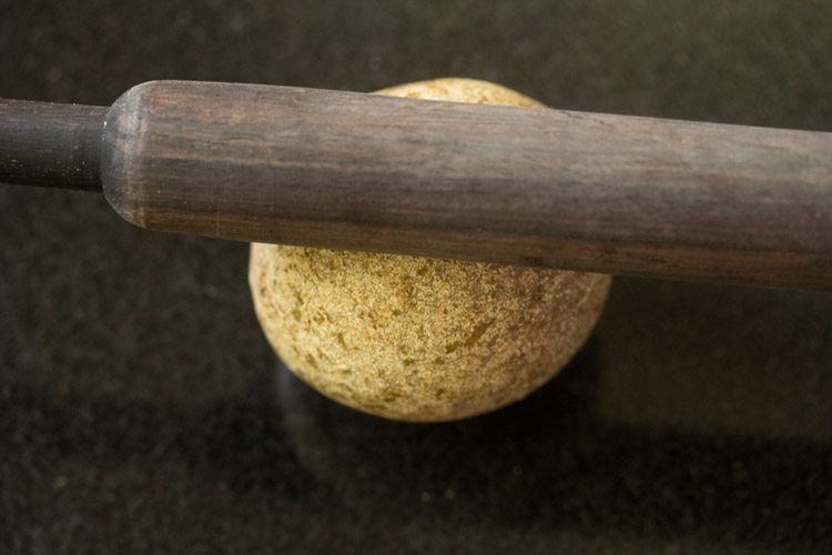 hitting wood apple fruit with a rolling pin.