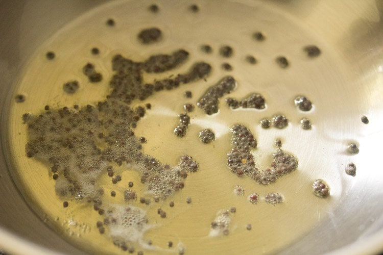 mustard seeds added to hot sesame oil in pan. 