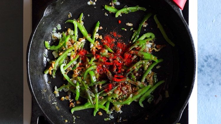 bright red kashmiri chili powder added to pan with peppers and aromatics