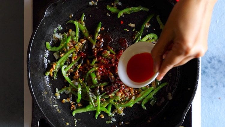 hand pouring in red chilli sauce