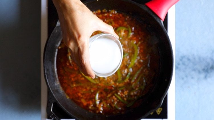 pouring the slurry into the pan with the chilli paneer sauce