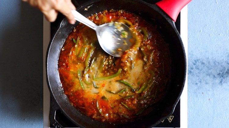 hand vigorously stirring the slurry into the chilli sauce