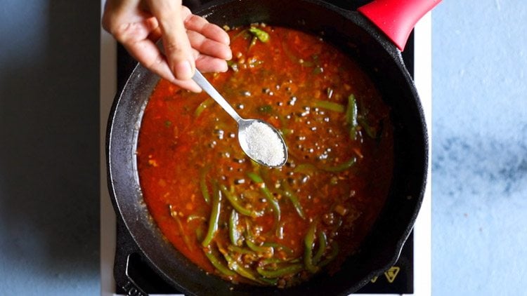 teaspoon of sugar being held above pan