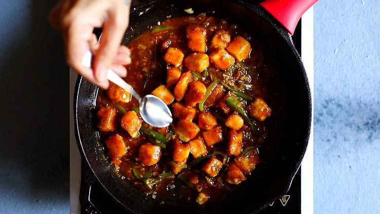 vinegar being added to restaurant style chilli paneer after cooking