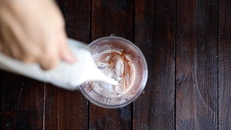 adding chilled milk to blender jar. 