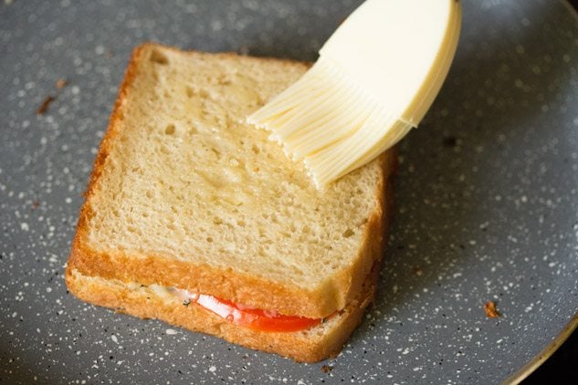 brushing butter on the sandwich. 