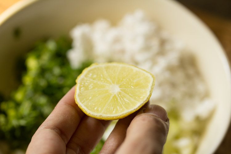 squeezing a slice of lemon into the bowl. 
