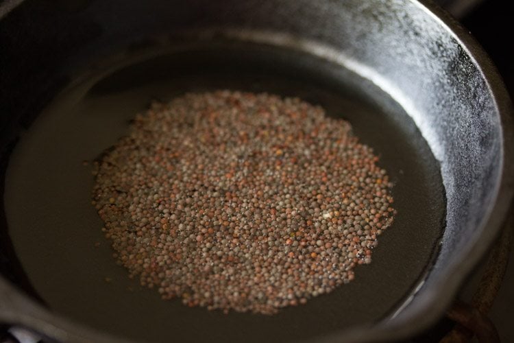 mustard seeds added to hot oil in a pan for making tempering. 