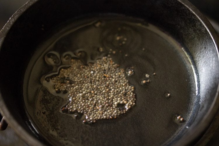 mustard seeds crackling in hot oil in a small pan for making tempering. 