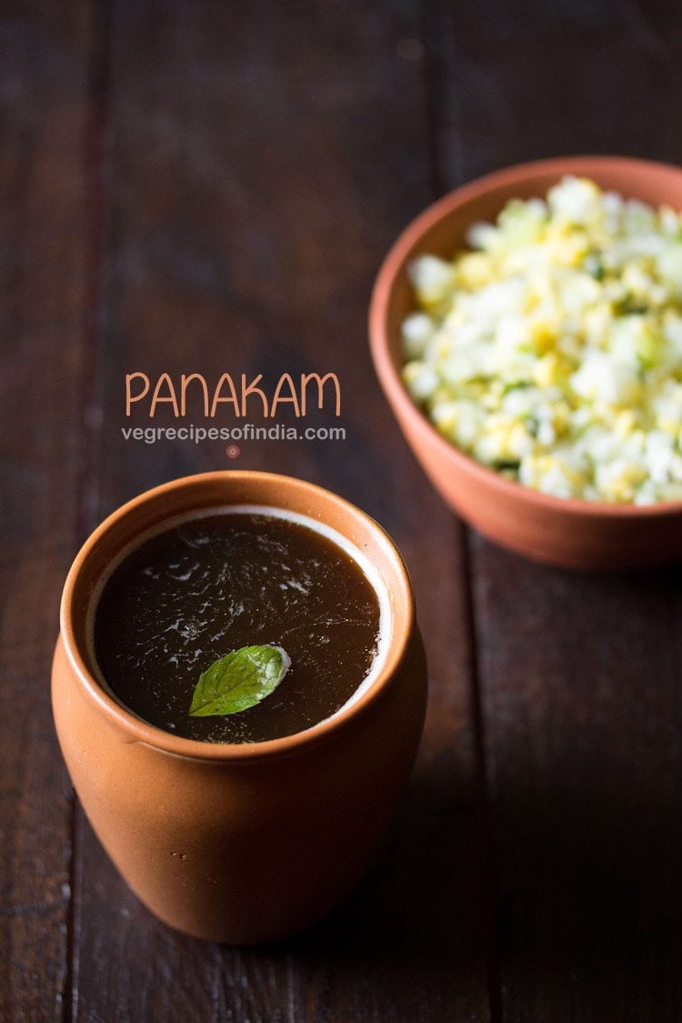 panakam garnished with a tulsi leaf and served in a earthen glass with text layovers.