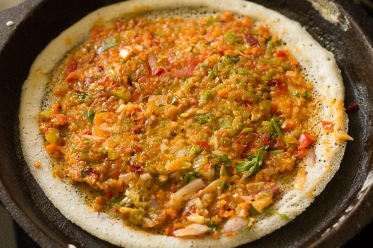 vegetable mixture spread evenly on schezwan dosa. 