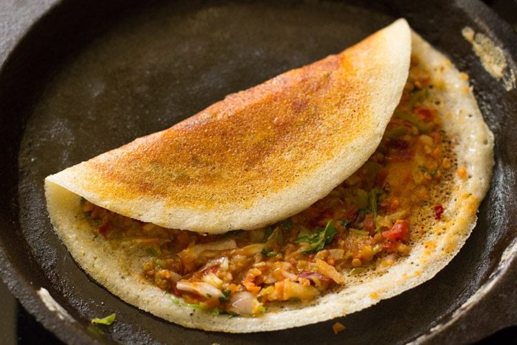 cooking and folding schezwan dosa. 