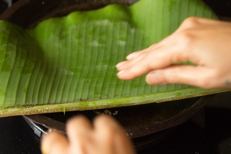 placing plantain leaf and akki roti dough on skillet