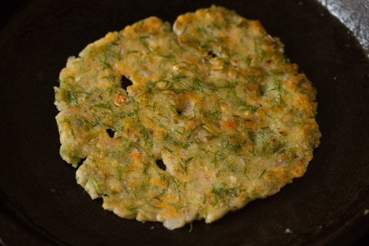 flipping and cooking akki roti on skillet