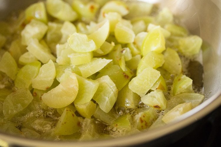 chopped amla pieces added to the hot oil in pan.