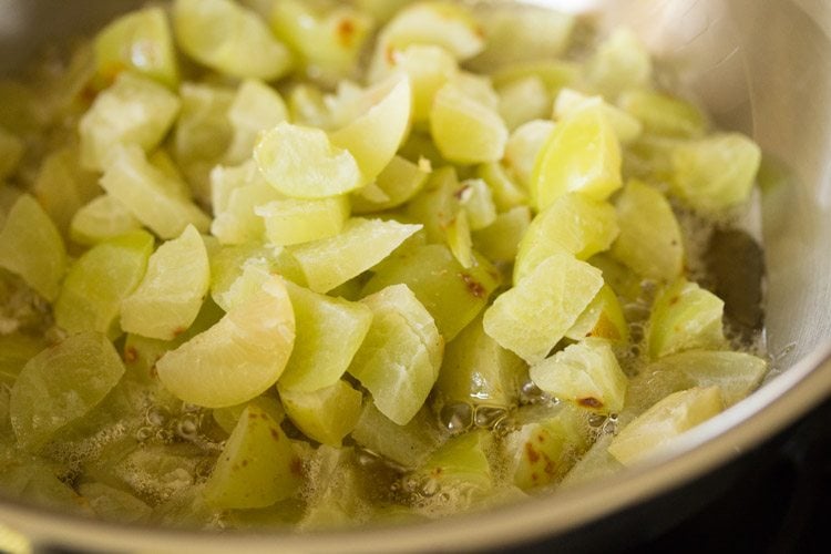 chopped amla pieces added to the hot oil in pan. 