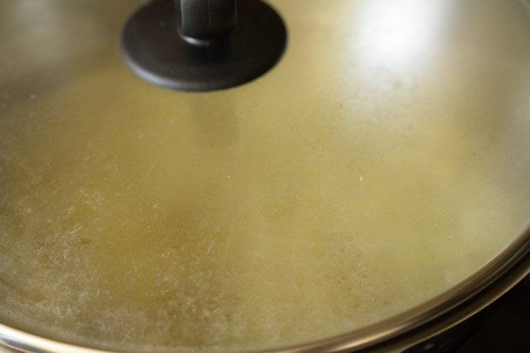 covering the pan to cook the amla pieces.
