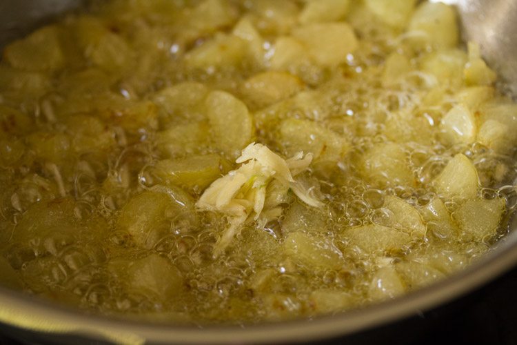 adding crushed garlic to the amla pieces in pan 