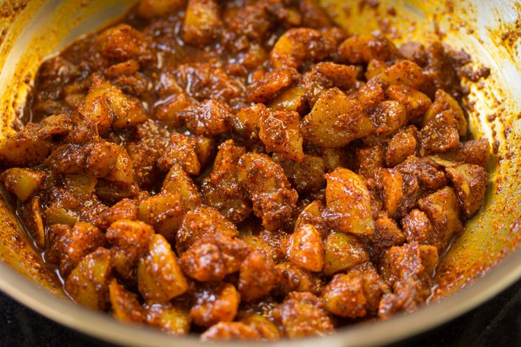mixing the spice powders with the amla pieces in the pan.