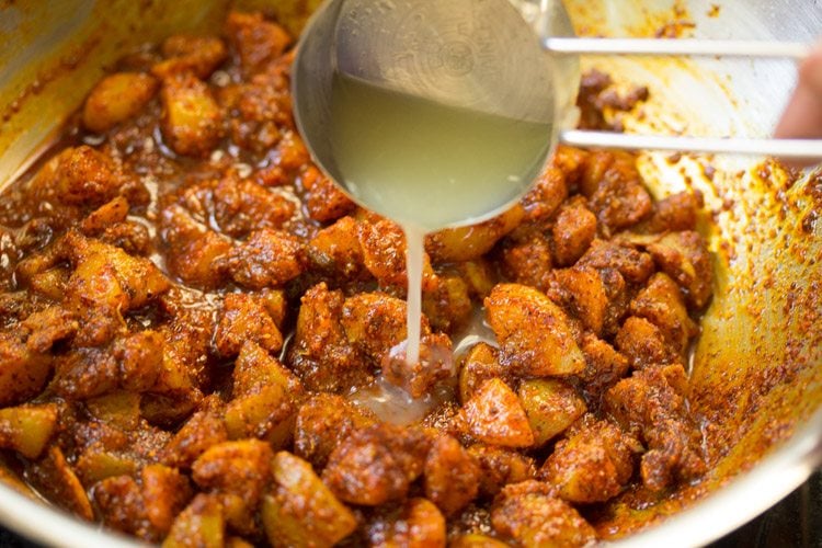 adding lemon juice to the spiced amla pieces in the pan.