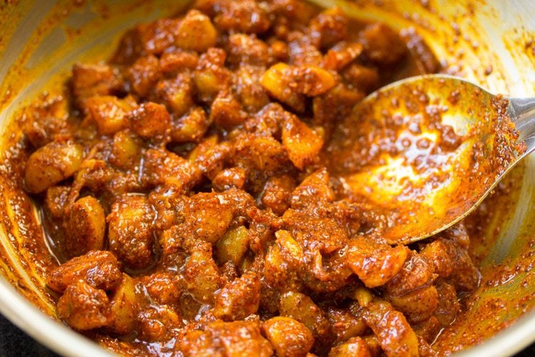 mixing spiced amla pieces in the pan to make amla ka achar. 