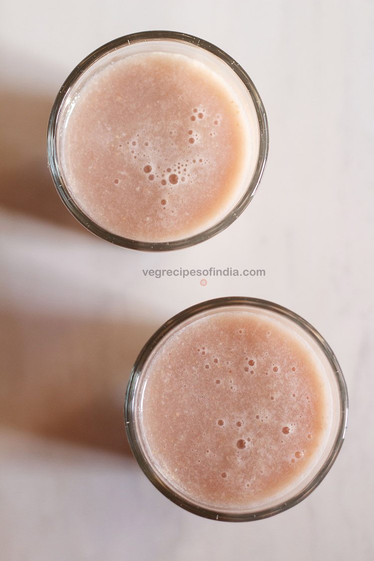 overhead shot of two glasses of anar juice on a white table from my pomegranate juice recipe