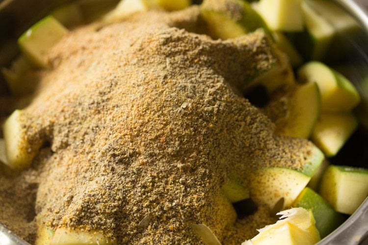 adding fenugreek powder to the mango pieces 