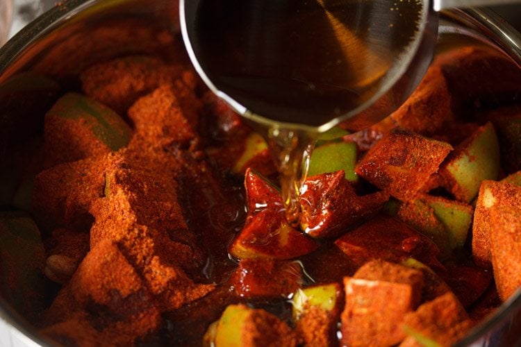 adding sesame oil to the spiced mangoes 