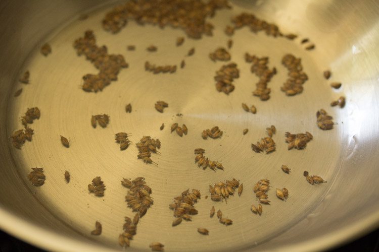 cumin seeds spluttering in hot oil in a pan. 