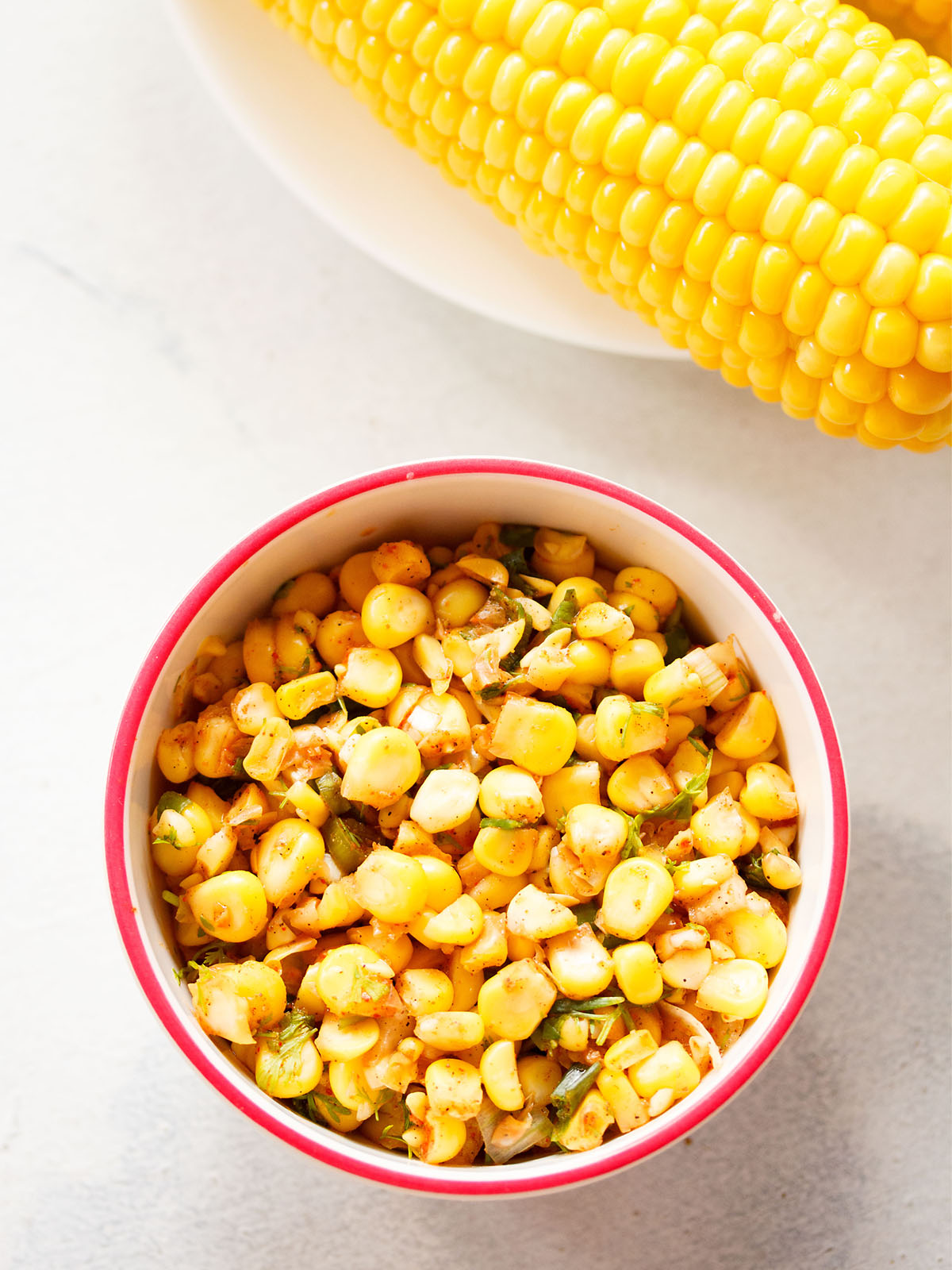 sweet corn salsa served in a dark pink rimmed white bowl on a white background