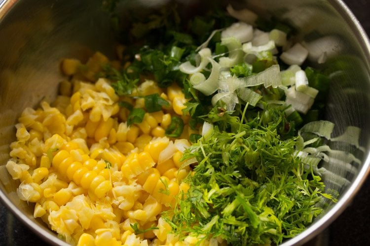 corn, green chilies, cilantro, onions in a steel mixing bowl