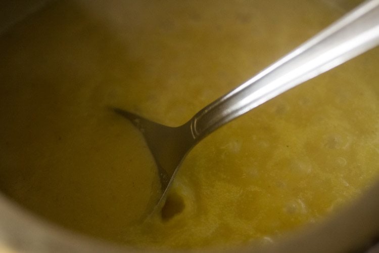 simmering moong dal curry while stirring at intervals. 