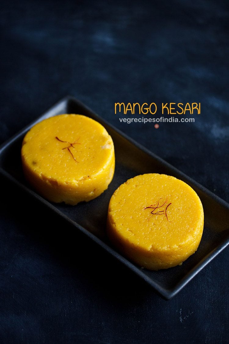 mango kesari garnished with saffron and served on a black platter. 