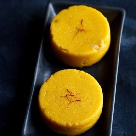 mango kesari garnished with saffron and served on a black platter.