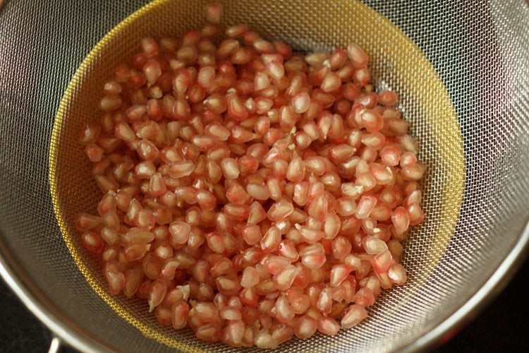 pomegranate arils drained in mesh strainers