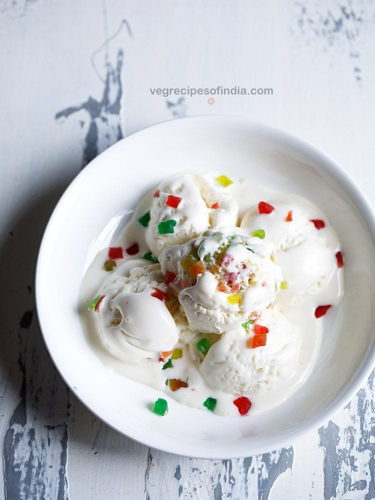 tutti frutti ice cream scoops garnished with tutti frutti and served in a white bowl 