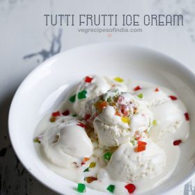 tutti frutti ice cream scoops garnished with tutti frutti and served in a white bowl.