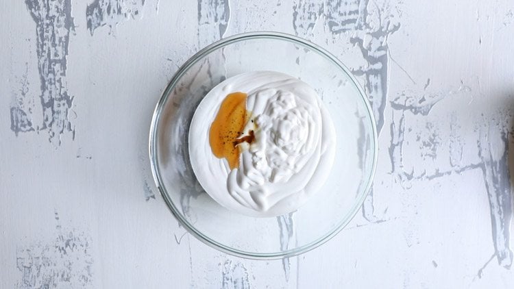 adding chilled whipping cream and vanilla extract in a bowl 