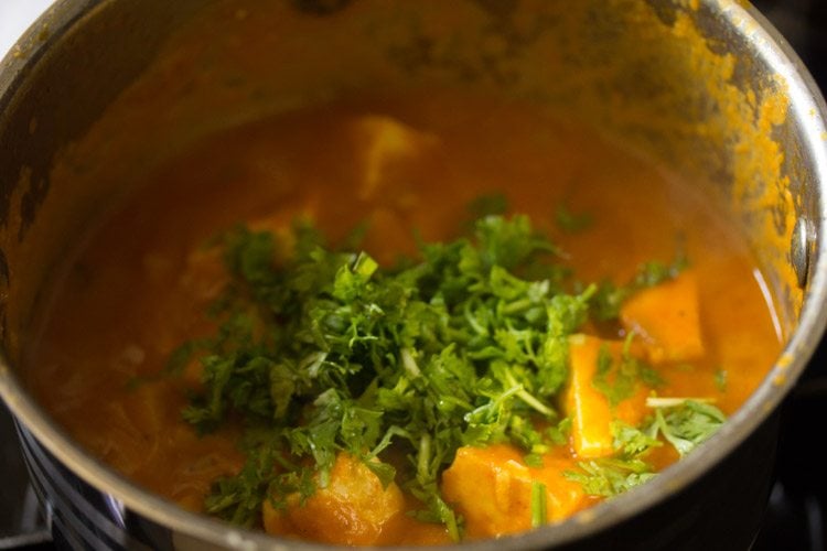 adding chopped coriander leaves to aloo paneer 