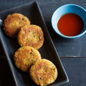 bread cutlet served on a black platter with a blue bowl of tomato ketchup kept on the right side and text layovers.