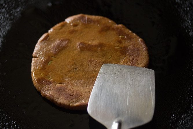 pressing jaggery roti with spatula